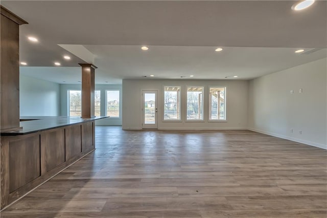 unfurnished living room with light wood-type flooring and ornate columns