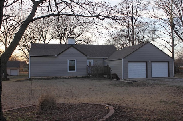 rear view of property featuring an outdoor structure and a garage