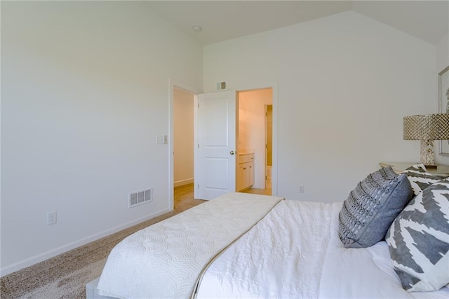 bedroom with carpet, ensuite bathroom, and vaulted ceiling