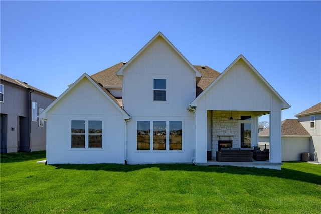 back of property with central air condition unit, a yard, and a fireplace