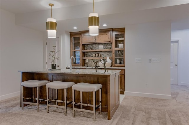 bar with light carpet, sink, hanging light fixtures, and light stone countertops