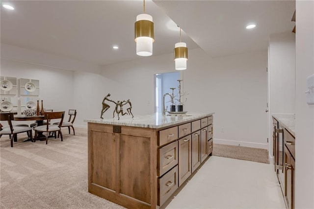 kitchen with sink, hanging light fixtures, a kitchen island with sink, light carpet, and light stone counters