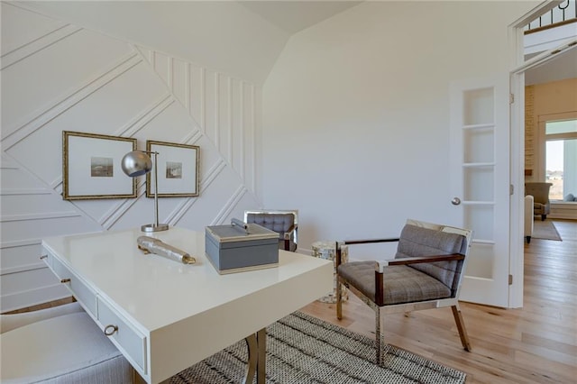 office featuring built in shelves, light hardwood / wood-style flooring, and vaulted ceiling