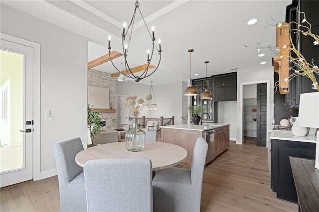 dining space featuring a notable chandelier, light hardwood / wood-style flooring, a fireplace, and sink