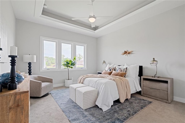 carpeted bedroom with ceiling fan and a raised ceiling