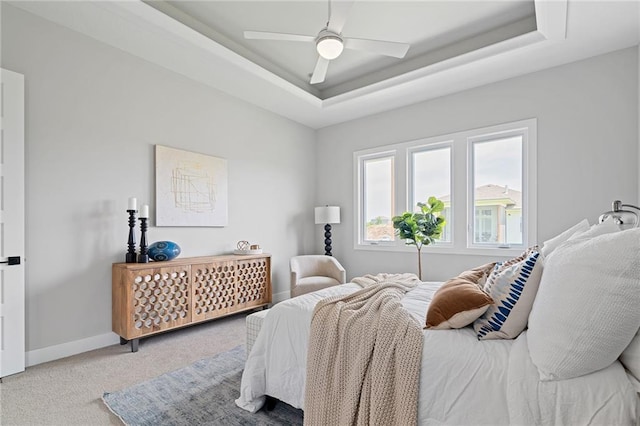 bedroom with a raised ceiling, carpet flooring, and ceiling fan