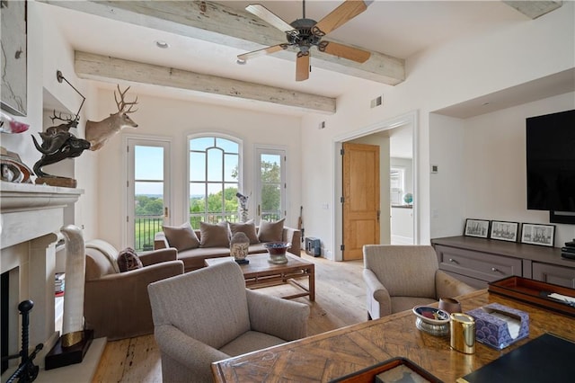 living room with ceiling fan, beam ceiling, a fireplace, and light hardwood / wood-style floors