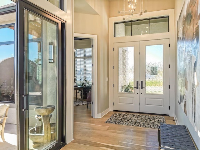 foyer with a notable chandelier, light hardwood / wood-style floors, and french doors