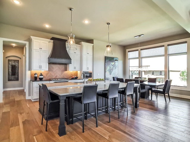 2908 NE 102nd St, Kansas City, MO 64155 - kitchen featuring a breakfast bar, custom range hood, wood-type flooring, and a kitchen island with sink