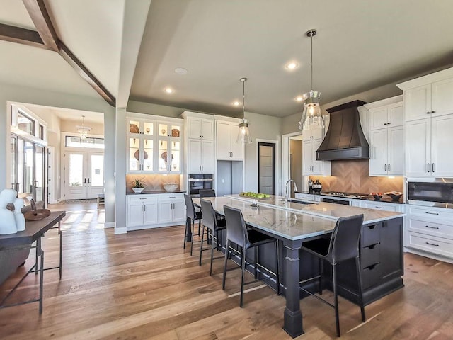 2908 NE 102nd St, Kansas City, MO 64155 - kitchen featuring hardwood / wood-style floors, appliances with stainless steel finishes, an island with sink, beam ceiling, and custom range hood