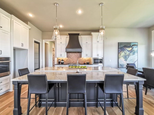 2908 NE 102nd St, Kansas City, MO 64155 - kitchen featuring decorative light fixtures, appliances with stainless steel finishes, tasteful backsplash, a center island with sink, and custom exhaust hood