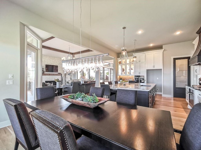 2908 NE 102nd St, Kansas City, MO 64155 - dining space with light hardwood / wood-style flooring, sink, a fireplace, and a chandelier