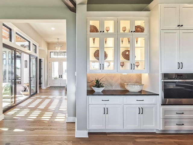 2908 NE 102nd St, Kansas City, MO 64155 - bar with backsplash, white cabinets, hardwood / wood-style flooring, and oven