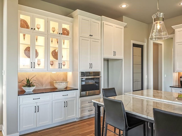 2908 NE 102nd St, Kansas City, MO 64155 - kitchen with decorative light fixtures, dark wood-type flooring, white cabinets, backsplash, and oven