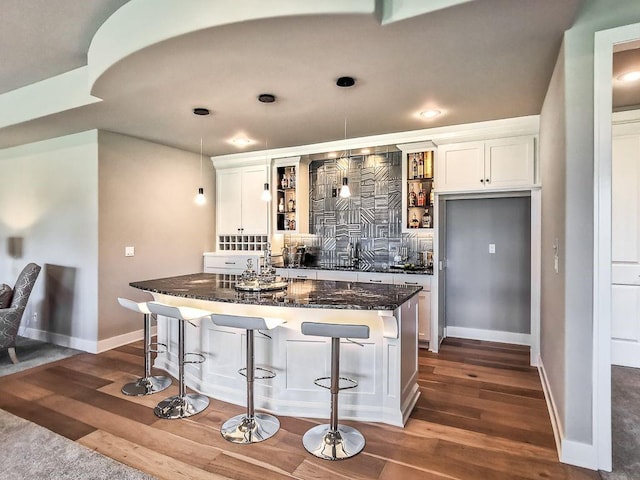 2908 NE 102nd St, Kansas City, MO 64155 - kitchen featuring a kitchen breakfast bar, white cabinets, dark wood-type flooring, and dark stone countertops