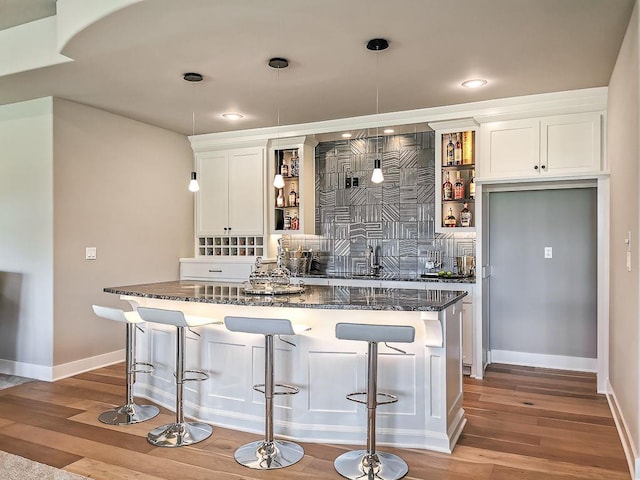 2908 NE 102nd St, Kansas City, MO 64155 - kitchen with light hardwood / wood-style floors, hanging light fixtures, white cabinetry, and a breakfast bar