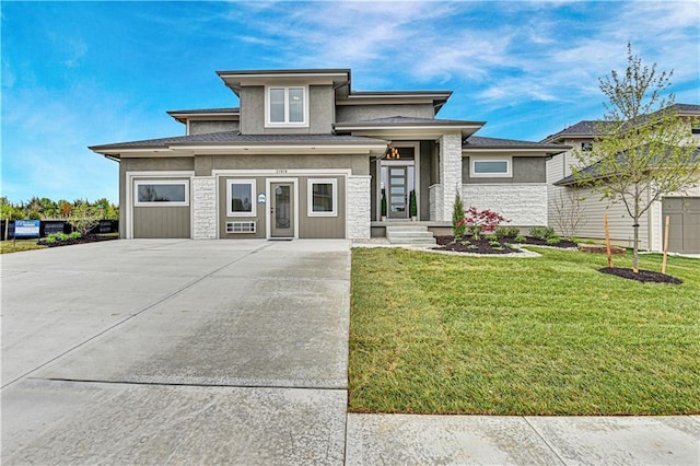 prairie-style house featuring a garage and a front lawn