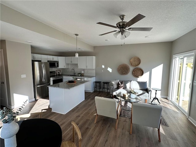 living room with a textured ceiling, ceiling fan, dark hardwood / wood-style floors, and a wealth of natural light