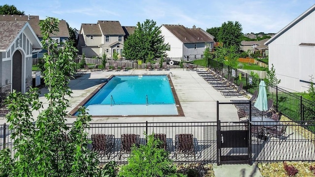 community pool with fence, a patio area, and a residential view