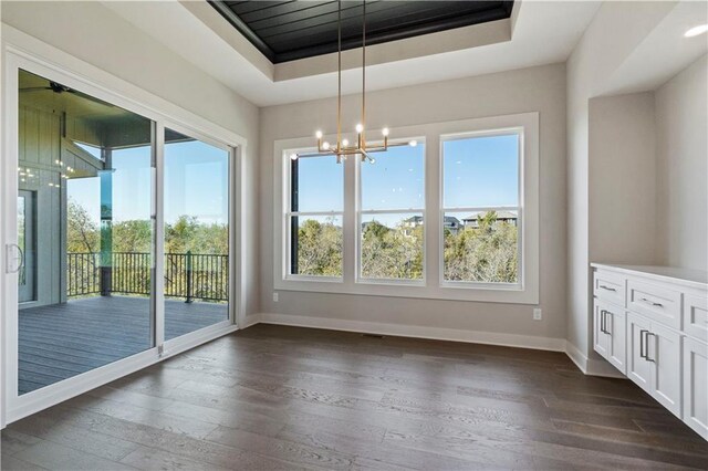 11606 S Zarda Dr, Olathe, KS 66061 - unfurnished dining area with baseboards, a raised ceiling, a notable chandelier, and dark wood-style flooring