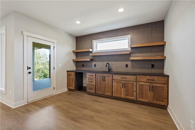 11606 S Zarda Dr, Olathe, KS 66061 - kitchen featuring tasteful backsplash, open shelves, dark countertops, light wood finished floors, and a sink