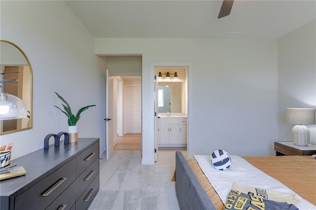 bedroom featuring ensuite bath, ceiling fan, sink, and light colored carpet