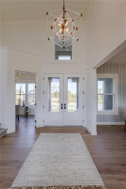 entrance foyer with dark hardwood / wood-style floors, an inviting chandelier, a healthy amount of sunlight, and french doors