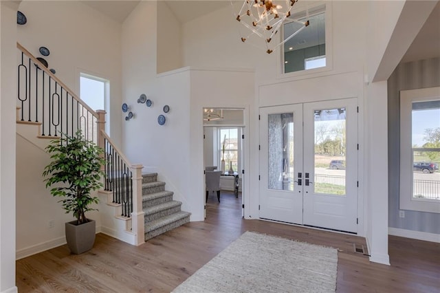 entrance foyer featuring french doors, an inviting chandelier, wood-type flooring, and a high ceiling