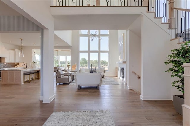 living room with sink, a notable chandelier, light wood-type flooring, and a high ceiling