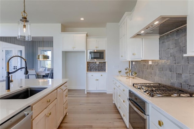 kitchen featuring light hardwood / wood-style flooring, stainless steel appliances, tasteful backsplash, and decorative light fixtures