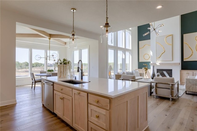 kitchen with decorative light fixtures, light wood-type flooring, light brown cabinetry, dishwasher, and sink