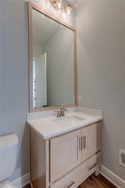 bathroom featuring toilet, vanity, hardwood / wood-style flooring, and a chandelier