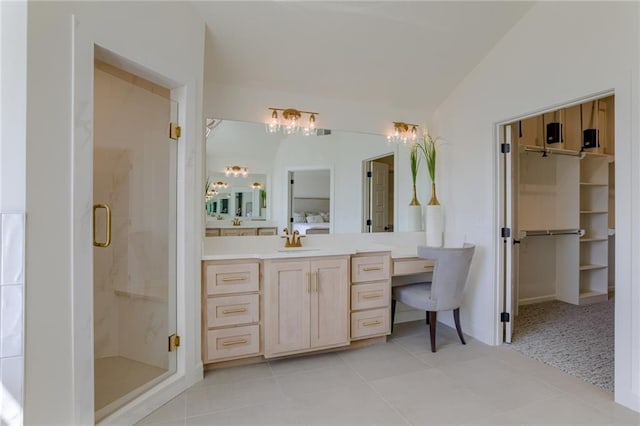 bathroom with a shower with door, vanity with extensive cabinet space, tile flooring, and vaulted ceiling