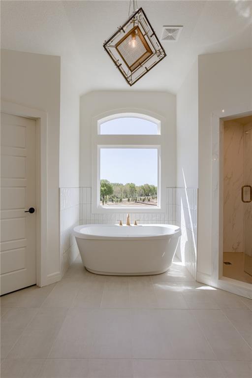 bathroom with shower with separate bathtub, tile floors, and tile walls