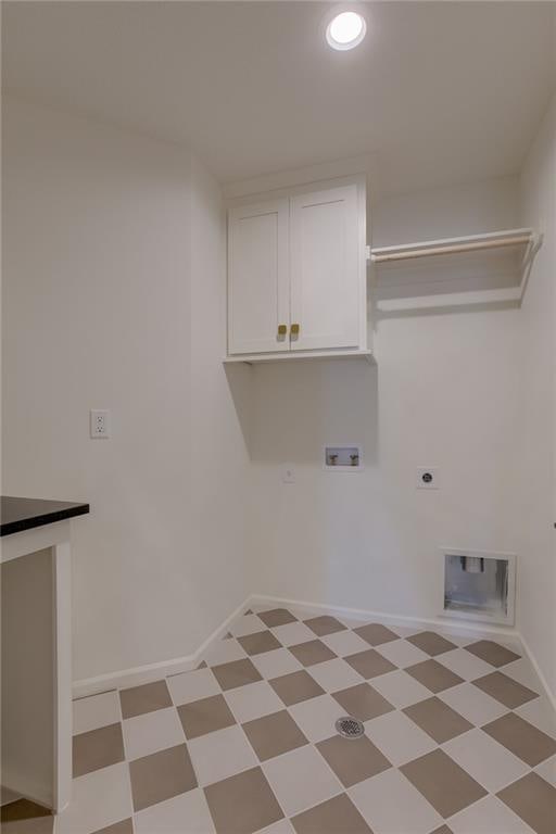 laundry area featuring electric dryer hookup, hookup for a washing machine, light tile floors, and cabinets