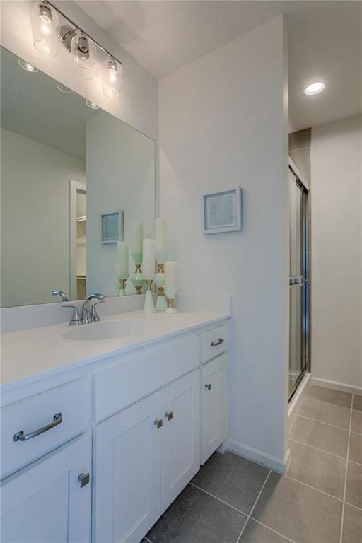 bathroom with tile floors, a shower with shower door, and vanity