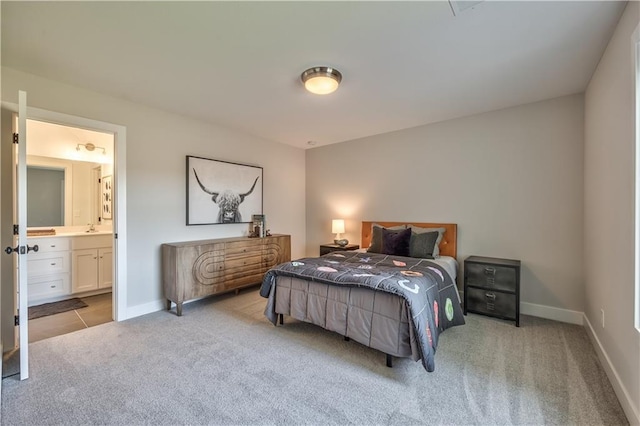 bedroom featuring light carpet, ensuite bath, and sink