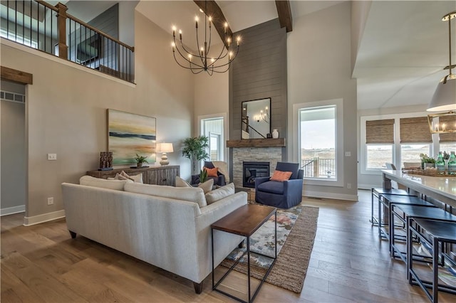 living room featuring a towering ceiling, a notable chandelier, hardwood / wood-style flooring, and a fireplace