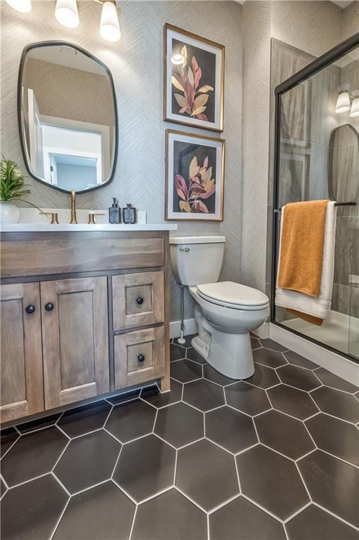 bathroom featuring oversized vanity, toilet, tile floors, and a shower with shower door