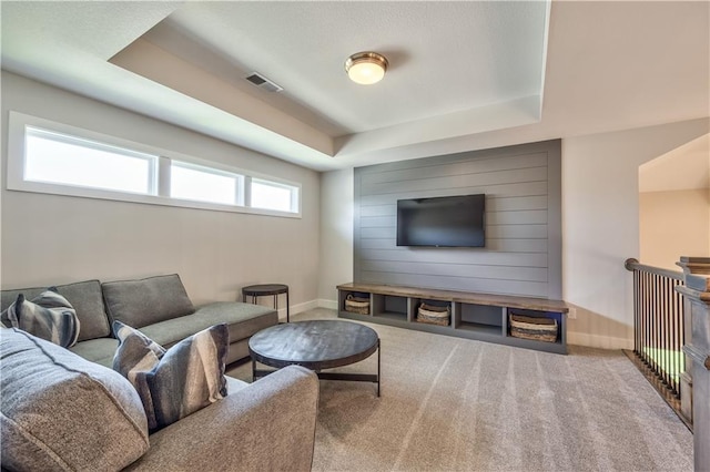 carpeted living room featuring a tray ceiling