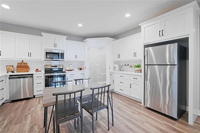 kitchen with white cabinets, light wood-type flooring, and stainless steel appliances