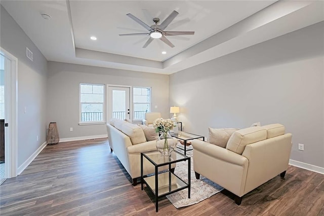 living room with ceiling fan, a raised ceiling, french doors, and dark wood-type flooring