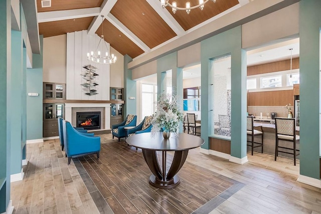 living room with a notable chandelier, high vaulted ceiling, beamed ceiling, and hardwood / wood-style flooring