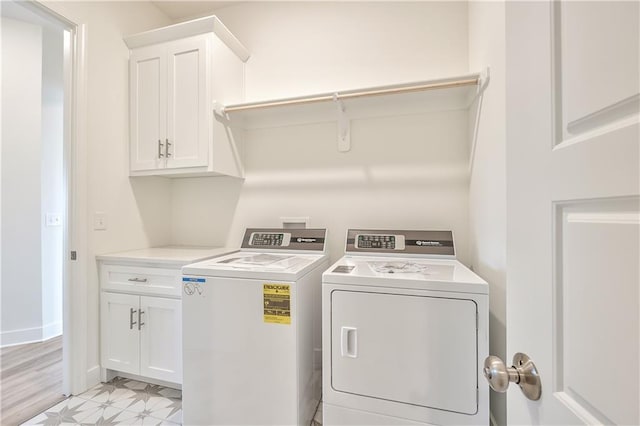 laundry room with separate washer and dryer, cabinets, and light wood-type flooring