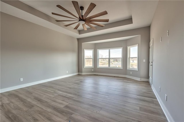 unfurnished room with light hardwood / wood-style flooring and a tray ceiling