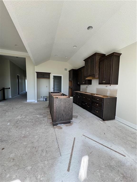 kitchen with dark brown cabinets, a textured ceiling, vaulted ceiling, and a center island