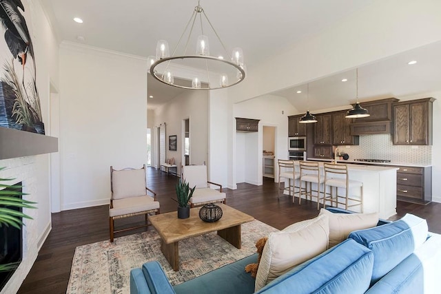 living room featuring crown molding, a large fireplace, vaulted ceiling, a notable chandelier, and dark hardwood / wood-style floors