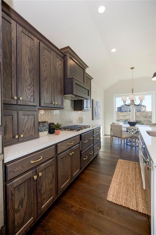 kitchen with dark brown cabinetry, appliances with stainless steel finishes, dark hardwood / wood-style floors, a notable chandelier, and vaulted ceiling