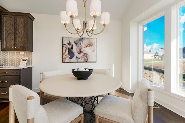 dining room featuring a notable chandelier, lofted ceiling, and dark hardwood / wood-style floors