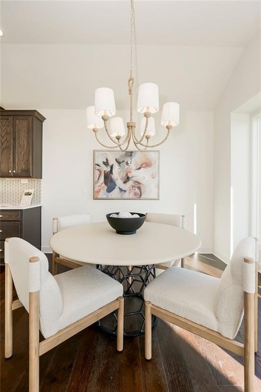 dining room featuring lofted ceiling, a chandelier, and hardwood / wood-style flooring